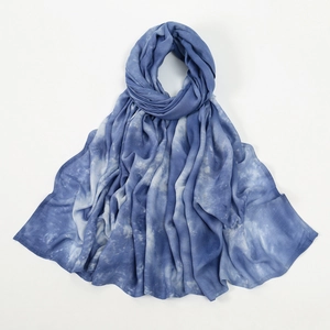 Détail de la texture tie-dye douce et des dégradés de bleu sur l'écharpe en coton léger