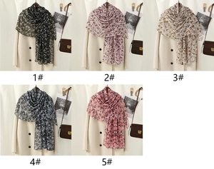 Detail of floral chiffon scarves in five colors displayed on a beige coat with texture