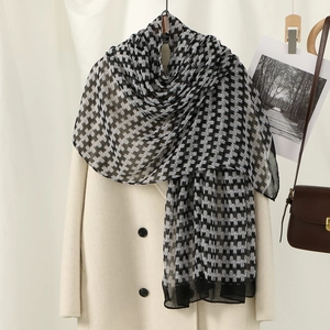 Close-up of lightweight black and white houndstooth scarf draped on a beige wool coat