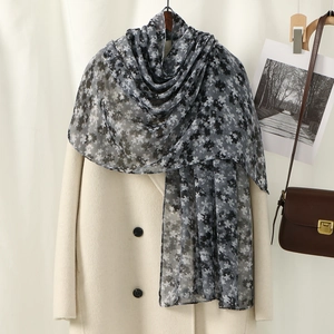 Floral print voile scarf in grey tones elegantly draped over a cream coat for sun protection