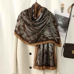 Brown linen cotton leaf print long scarf draped over an elegant cream coat for women