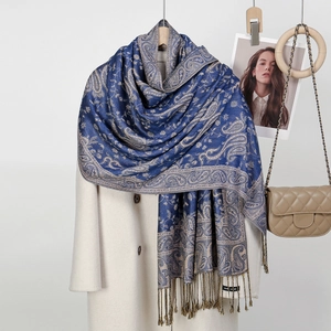 Dark blue paisley scarf with gold floral patterns and tassels over a white coat