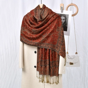 Elegant rust red paisley printed shawl with long tassels draped on an overcoat