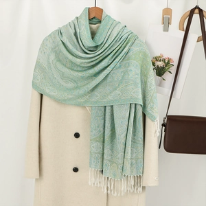 Elegant mint green paisley jacquard scarf with long white tassels on a beige coat