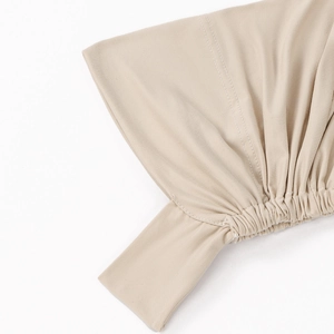 Detailed close-up of elastic shirring and stitching on a beige milk silk turban hat