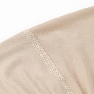 Detailed close-up of high-quality flat-lock stitching on soft beige milk silk fabric