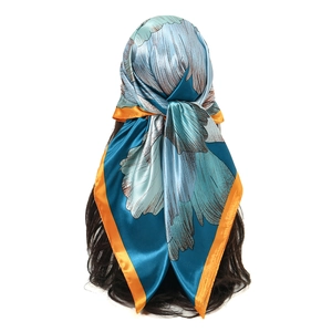 Floral satin square scarf with blue and orange contrast print worn as a headpiece