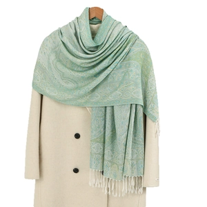 Pale green Paisley jacquard shawl with white fringe styled on a classic beige wool coat