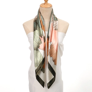Detail of silk-like satin square scarf with vibrant floral print draped on a mannequin