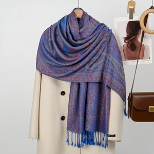 Elegant blue paisley shawl scarf with long tassels draped over a minimalist winter coat