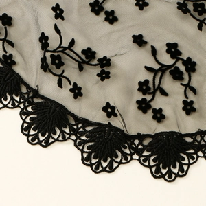 Macro view of delicate black floral lace fabric with intricate embroidery and scalloped edges