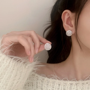 Elegant silver woven hollow sphere stud earrings for women shown on a model