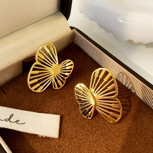 Detail of gold butterfly earrings with hollow radial lines in a premium jewelry box