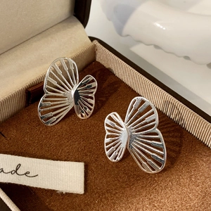 Detailed close-up of silver butterfly earrings with hollow metallic wing textures