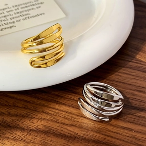 Minimalist multi-layered spiral rings in polished gold and silver finishes on a ceramic plate