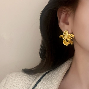 Boucles d'oreilles fleurs dorées irrégulières avec pétales texturés sur mannequin