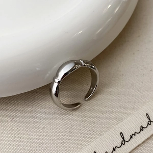 Detail of silver adjustable open ring with three pebble-shaped accents on ceramic plate