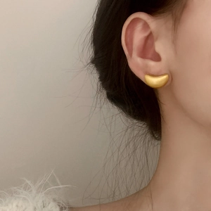 Minimalist matte gold bean-shaped stud earrings worn by model for elegant styling