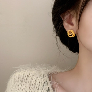 Elegant gold intertwined double hoop earrings with white pearl accent on model