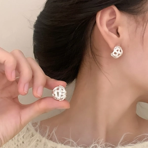 Minimalist woven hollow sphere earrings in silver, elegantly worn for a modern style