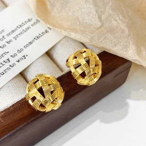 Detail shot of golden woven sphere earrings displayed on a dark wooden jewelry stand
