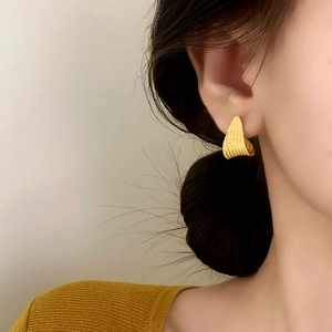 Elegant gold triangular textured geometric stud earrings shown worn on a female model
