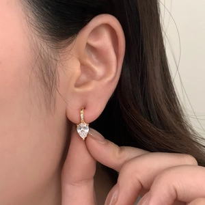 Gros plan de boucles d'oreilles pendantes dorées en forme de goutte portées par un mannequin