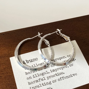 Detailed view of silver geometric hoop earrings with smooth and textured metal finish