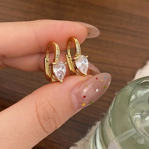 Gros plan sur des boucles d'oreilles en goutte dorées serties de zircons brillants
