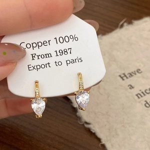 Détail de boucles d'oreilles en cuivre pur avec zircons taillés en poire dorés