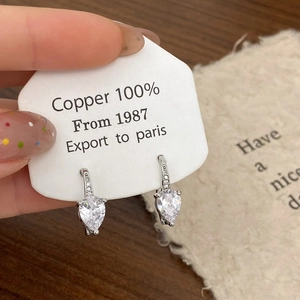 Gros plan de boucles d'oreilles cœur en zircon argenté sur carte de cuivre