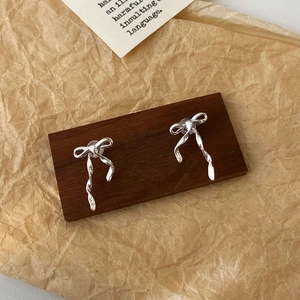 Détail macro de boucles d'oreilles nœud argenté avec pendentifs spirale sur fond bois