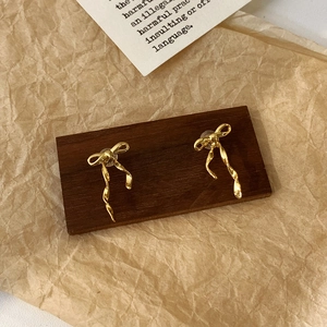 Gros plan de boucles d'oreilles nœud doré avec pompons spirales sur bois