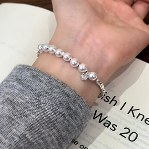 Elegant pearl and silver bead bracelet with flower pendant worn on a model wrist