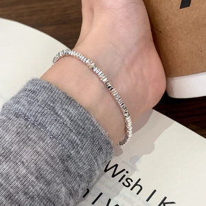 Elegant faceted silver bead anklet with high shine finish on woman's ankle in cozy setting