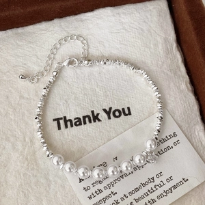 Elegant silver beaded bracelet with white pearls and sparkling star pendant on linen