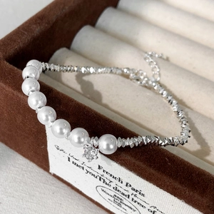Detail of elegant pearl and silver bead bracelet featuring a star charm on velvet