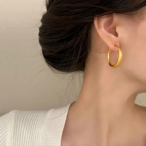 Elegant matte gold-plated hoop earrings for women worn by a model in a minimalist style