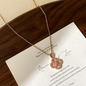 Macro detail of rose gold clover pendant with pink inlay and sparkling micro zircons
