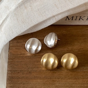 Gros plan de boucles d'oreilles rondes dorées et argentées à texture métallique plissée
