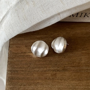Vue détaillée de boucles d'oreilles rondes en argent brossé avec texture froissée