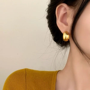 Retro gold C-shaped earrings with textured finish shown on a model in a side view