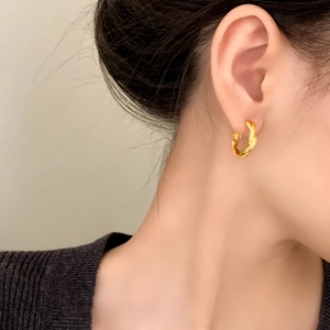 Classic golden twisted rope hoop earrings showcased on a model for a vintage elegant look
