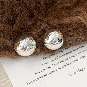 Détail macro de boucles d'oreilles boules argentées texturées avec finition brossée et douce