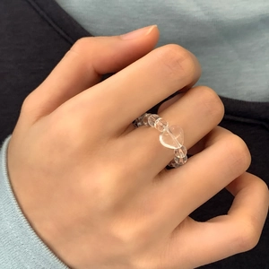 Minimalist transparent heart-shaped glass bead ring worn on hand for a chic look