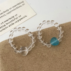 Minimalist striped glass bead rings with transparent and blue heart charms in high detail