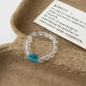 Detailed macro view of a minimalist handmade ring with blue heart and clear beads