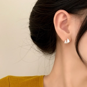 Minimalist matte silver geometric hoop earrings shown on model with warm lighting
