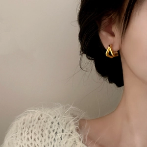 Minimalist gold triangle earrings with matte finish shown on model with cozy white knitwear