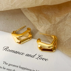Macro shot of double-layered U-shaped gold geometric earrings on a display card